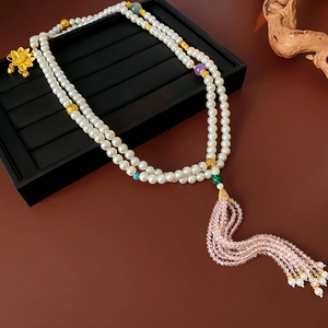 Detail of beaded necklace with golden lotus pendant and pink crystal tassels