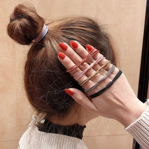 Elastic hair ties in multiple colors shown on model with a high-bun hairstyle
