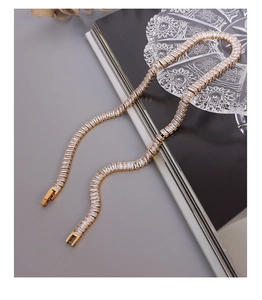Detailed view of gold tennis necklace featuring baguette-cut zircon stones on a gray background