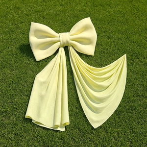 Large light yellow decorative velvet bow displayed on fresh green grass background