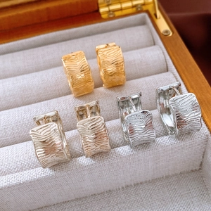 Detailed texture of 18K gold plated wrinkled C-shape earrings on jewelry display