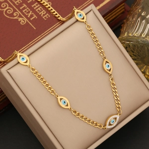 Detail of gold evil eye necklace with blue crystals in a beige jewelry gift box
