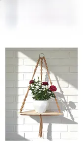 Detail of bohemian handmade woven wall shelf with triangular wood plate and cotton rope