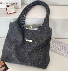 Détail du sac cabas en feutre gris foncé avec motif d'étoiles et doublure à carreaux