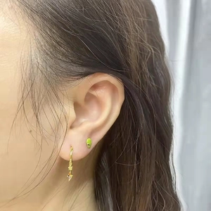 Star and moon gold hoop earrings with colorful crystals on a model's ear