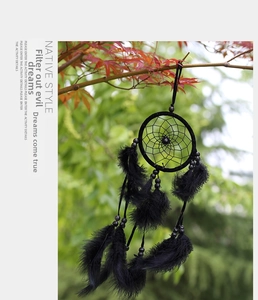 Detailed view of handmade black dream catcher with feathers hanging on an autumn tree branch