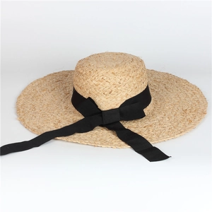 Elegant wide brim raffia sun hat for women featuring a black ribbon bow for summer beach