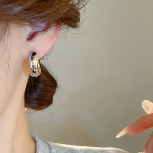 Primo piano di un orecchino a goccia d'argento con finitura a specchio sul modello