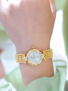 Close-up of golden quartz watch featuring a white dial with crystal hour markers on wrist