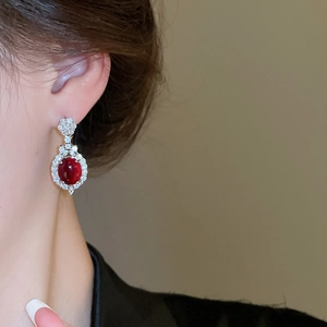 Close-up of red oval crystal earrings with diamond pavé on model for elegant look