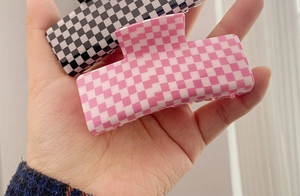 Close-up of square acetate hair claws featuring black and pink checkered patterns