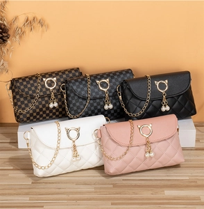 Detail of mini crossbody bags with cat-ear metal buckles and pearl pendants in five colors