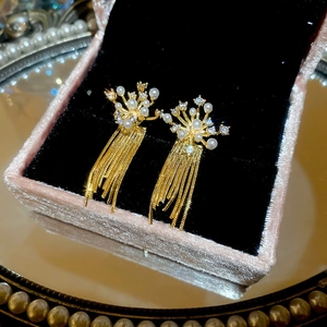 Detail shot of gold tassel earrings with pearls and rhinestones in a pink velvet jewelry box
