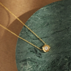 Detailed macro shot of a hexagonal 18K gold-plated pendant with a white zircon crystal