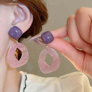 Detailed close-up of resin geometric earrings with purple square and pink striped design