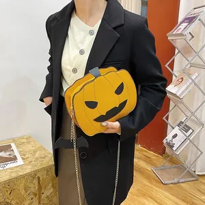 Detail of yellow pumpkin crossbody bag with black bat charm and gold chain strap