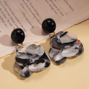 Detailed view of large marble texture resin flower drop earrings on vintage paper