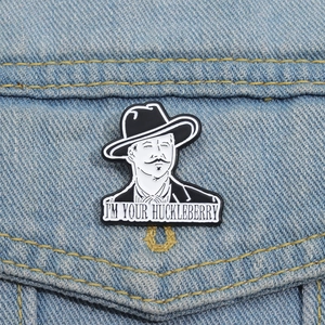 Enamel brooch with cowboy portrait and I'm Your Huckleberry text on denim jacket