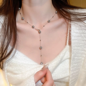 Close-up of elegant Y-shaped double layer necklace with grey pearls on model's neck
