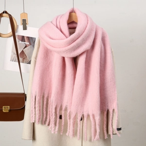 Détail d'une écharpe rose façon cachemire avec de longues franges sur un manteau