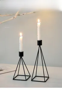 Close-up of minimalist black matte iron candle holders with pyramid geometric frame