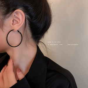 Minimalist matte black hoop earrings for women shown on a model in a side profile view