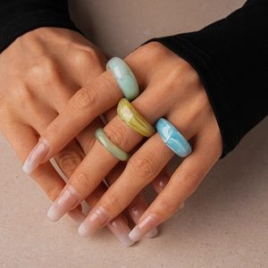 Close-up of stacked acrylic colorful resin rings in pastel tones on a model's hand