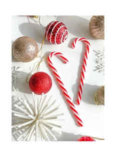 Flat lay of red and white candy cane ornaments with glittery Christmas tree decorations