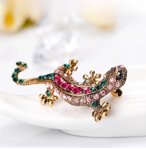 Macro shot of colorful rhinestones on a golden lizard brooch resting on white ceramic