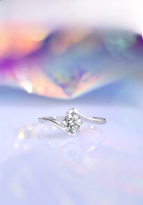 Macro view of 925 silver moissanite ring with four-prong setting on reflective surface