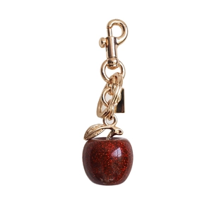 Close-up of glittery deep red apple pendant with golden metal hook for bag straps