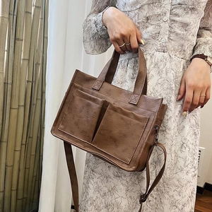 Brown faux leather tote bag detail with clear natural texture and dual front pockets