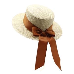 Détail d'un chapeau de paille beige avec un ruban gros-grain marron foncé et un joli nœud