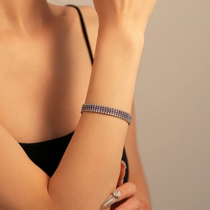 Gros plan d'un bracelet pavé à trois rangées avec pierres violettes sur un poignet féminin
