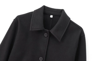 Detail of black lapel coat featuring soft texture fabric and two buttons with S size label