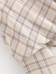 Detailed macro view of beige and lavender plaid fabric with precise stitching