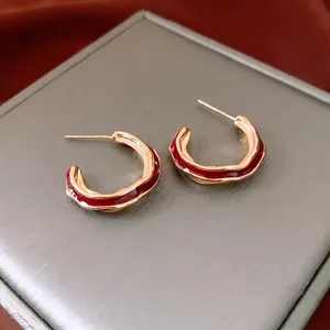 Gold-plated C-shaped hoop earrings with red enamel and textured lava ripple design