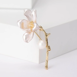 Detail of elegant white lily flower brooch with golden stem and a lustrous pearl