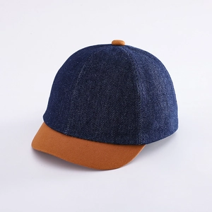 Dettaglio del cappellino da baseball in denim blu per bambini con visiera marrone a contrasto