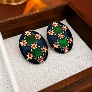Vintage oval enamel earrings with blue base and golden flower details on linen texture