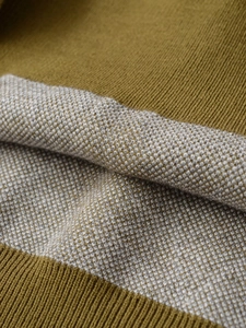 Macro texture of mustard yellow polo knitwear with grey honeycomb stitching patterns