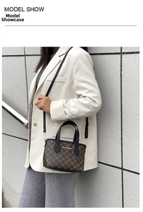 Nahaufnahme einer braunen Monogramm-Handtasche mit schwarzen Griffen an einem Modell