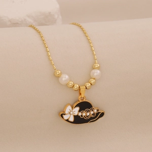 Detail of gold necklace with black enamel hat pendant, white bow, and delicate pearls