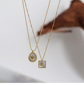 Close-up of gold crown and rose pendants with white shell inlay on titanium steel chain