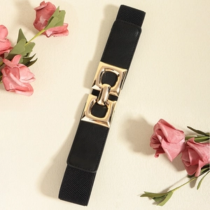 Close-up of black elastic belt with polished gold geometric buckle on a beige surface