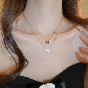 Dettaglio della collana a farfalla multistrato in acciaio dorato con perle finte