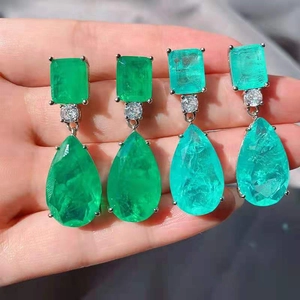 Macro detail of tear-drop pear cut emerald green stone earrings with silver frame