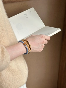 Detail of layered tiger eye and yellow crystal beads with golden charms on a wrist