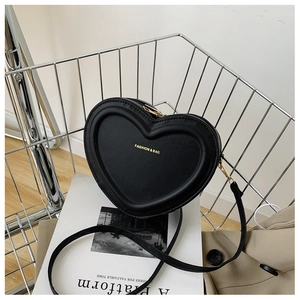 Détail d'un sac bandoulière en cuir noir en forme de cœur avec texte doré et fermeture