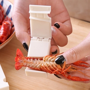 Manual plastic crayfish peeler tool with ergonomic handle shown on a wooden background